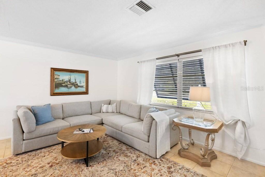 A living room features a light gray sectional sofa, a round coffee table, and a window — 4731 EGRET ROAD, VENICE, FL