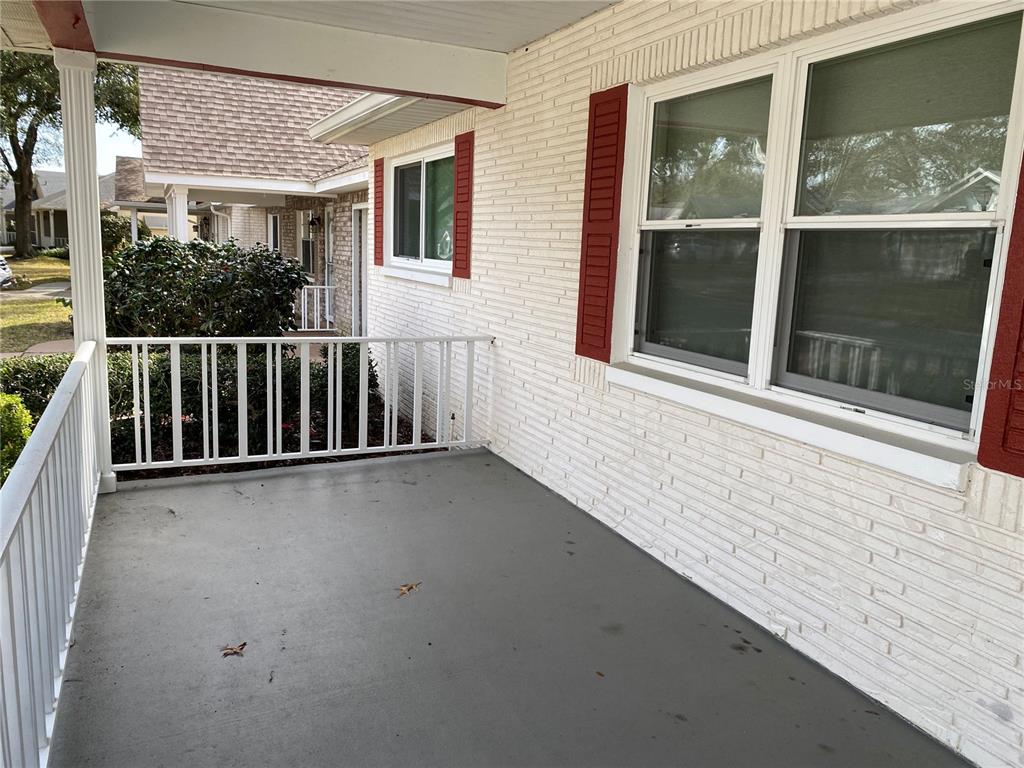 A covered front porch features white brick walls, red shutters, and a white metal railing — 8666 SW 92ND LANE UNIT C, OCALA, FL