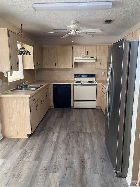 A kitchen features light wood cabinets, a stainless steel refrigerator, and grey wood-look flooring — 8666 SW 92ND LANE UNIT C, OCALA, FL