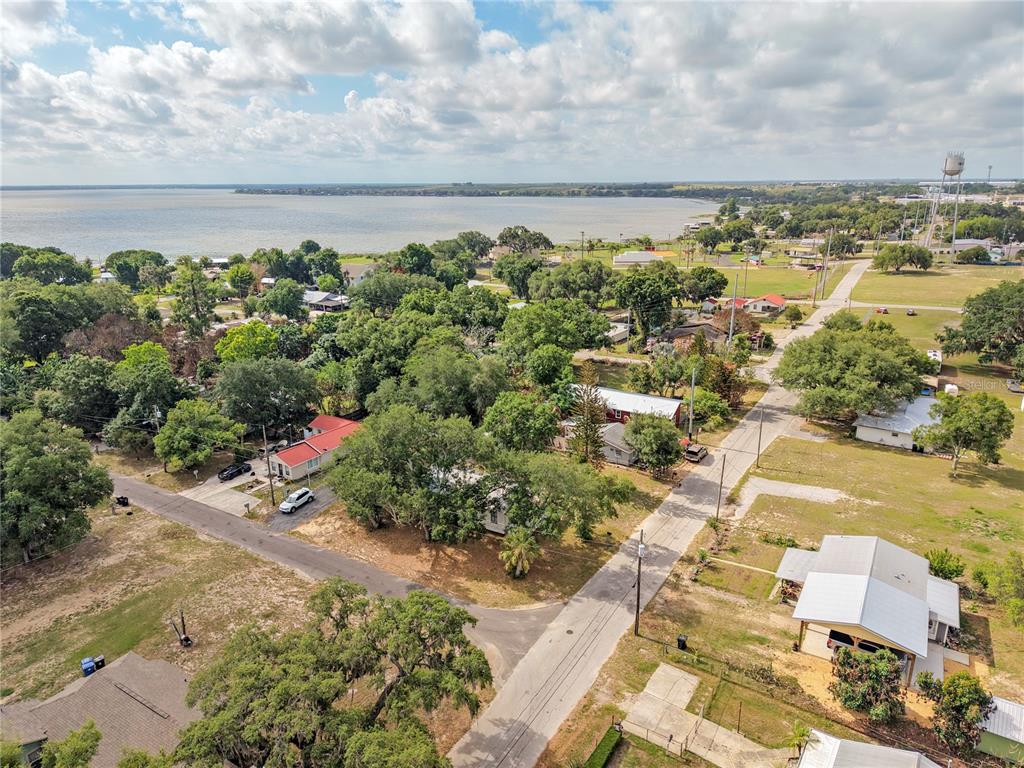 An aerial view shows houses nestled among trees near a large lake under a cloudy sky — 120 CHESNEY BOULEVARD, FROSTPROOF, FL