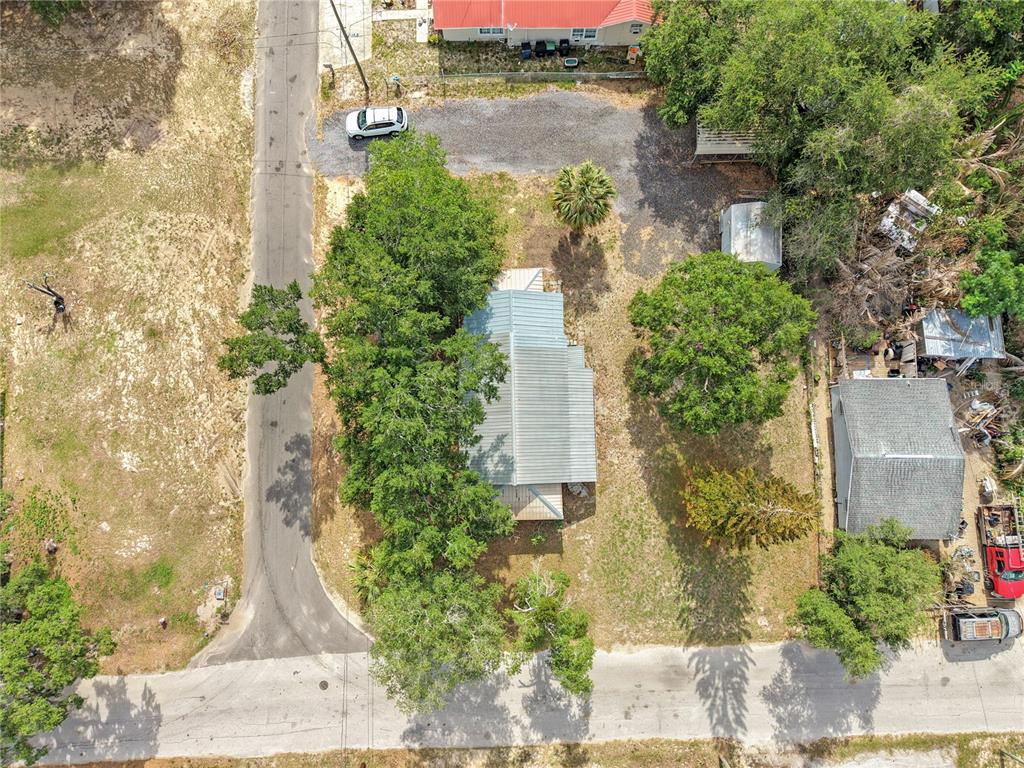 An aerial view shows a house with a metal roof surrounded by trees and gravel — 120 CHESNEY BOULEVARD, FROSTPROOF, FL