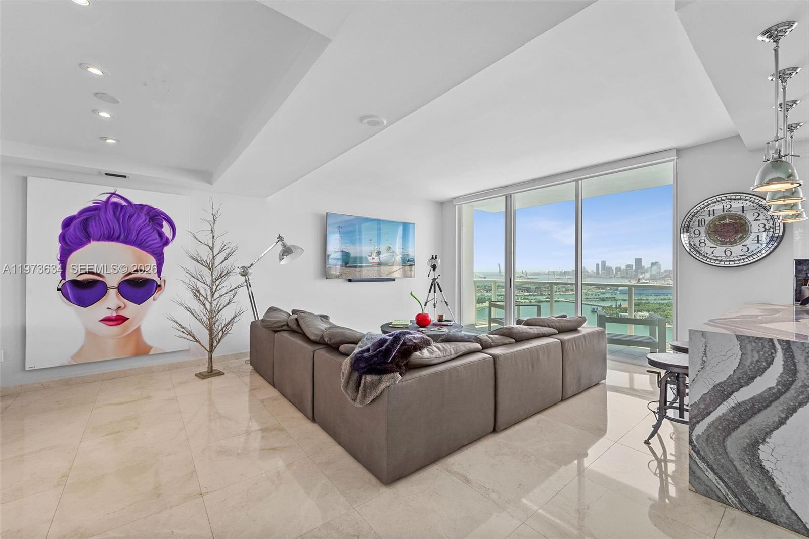 A modern living room features a large sectional sofa, wall art, and floor-to-ceiling windows — 650 West Ave, Miami Beach FL 33139, MIAMI BEACH, FL