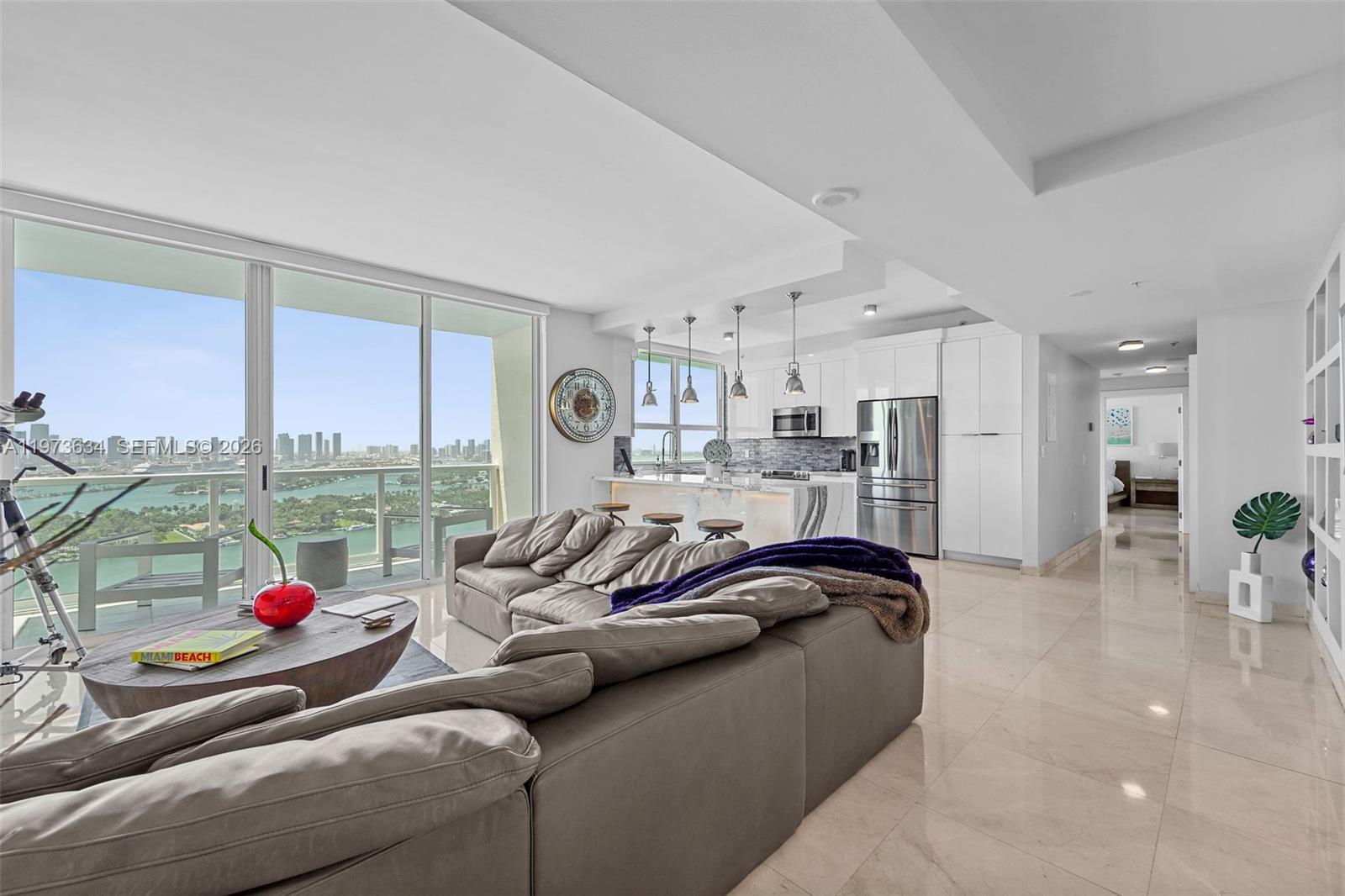A modern living room and kitchen area with floor-to-ceiling windows overlooking a city skyline — 650 West Ave, Miami Beach FL 33139, MIAMI BEACH, FL