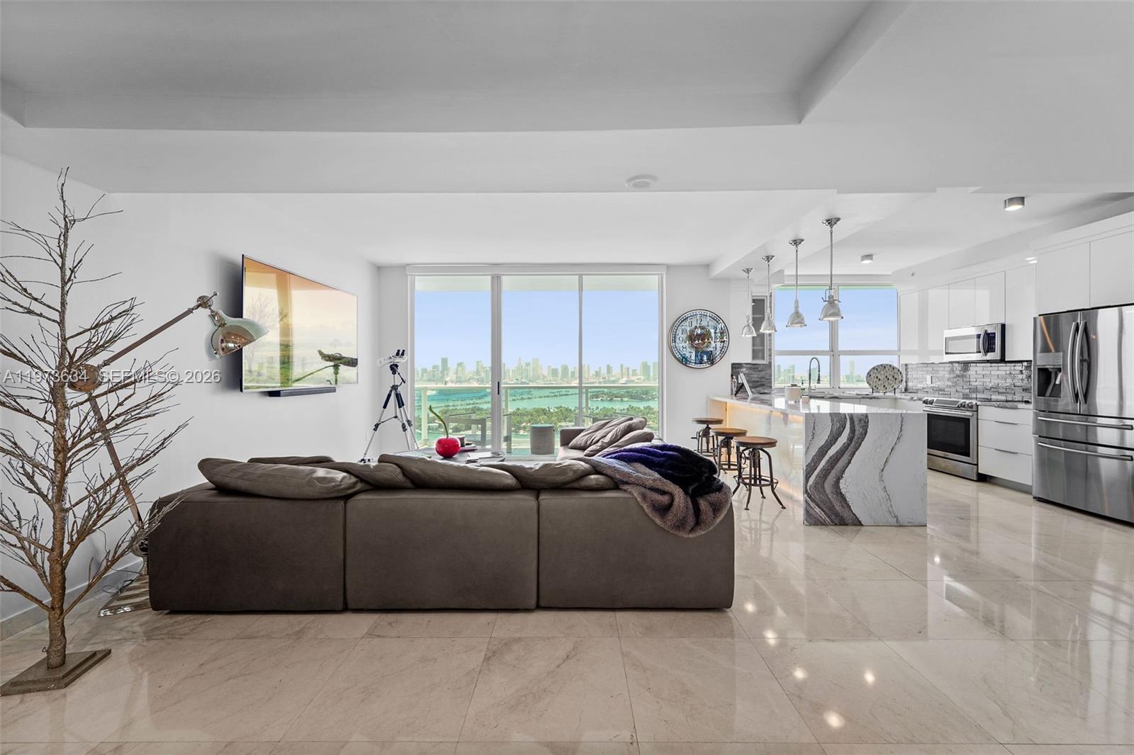 A modern open-concept living area features a kitchen with a marble island and city views — 650 West Ave, Miami Beach FL 33139, MIAMI BEACH, FL