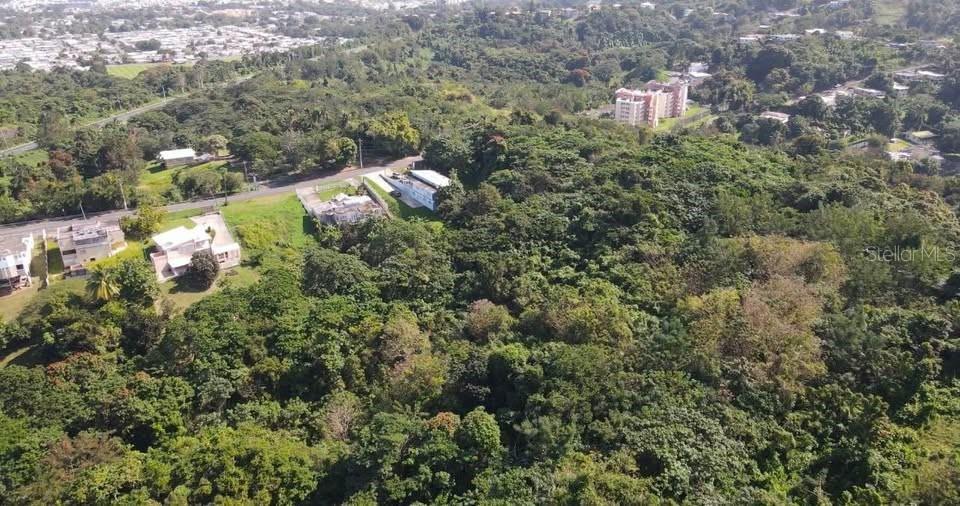 An aerial view shows a wooded hillside with several houses and a multi-story apartment building — Rd. 859 Km. 1.5 BO. SANTA CRUZ, CAROLINA, PR