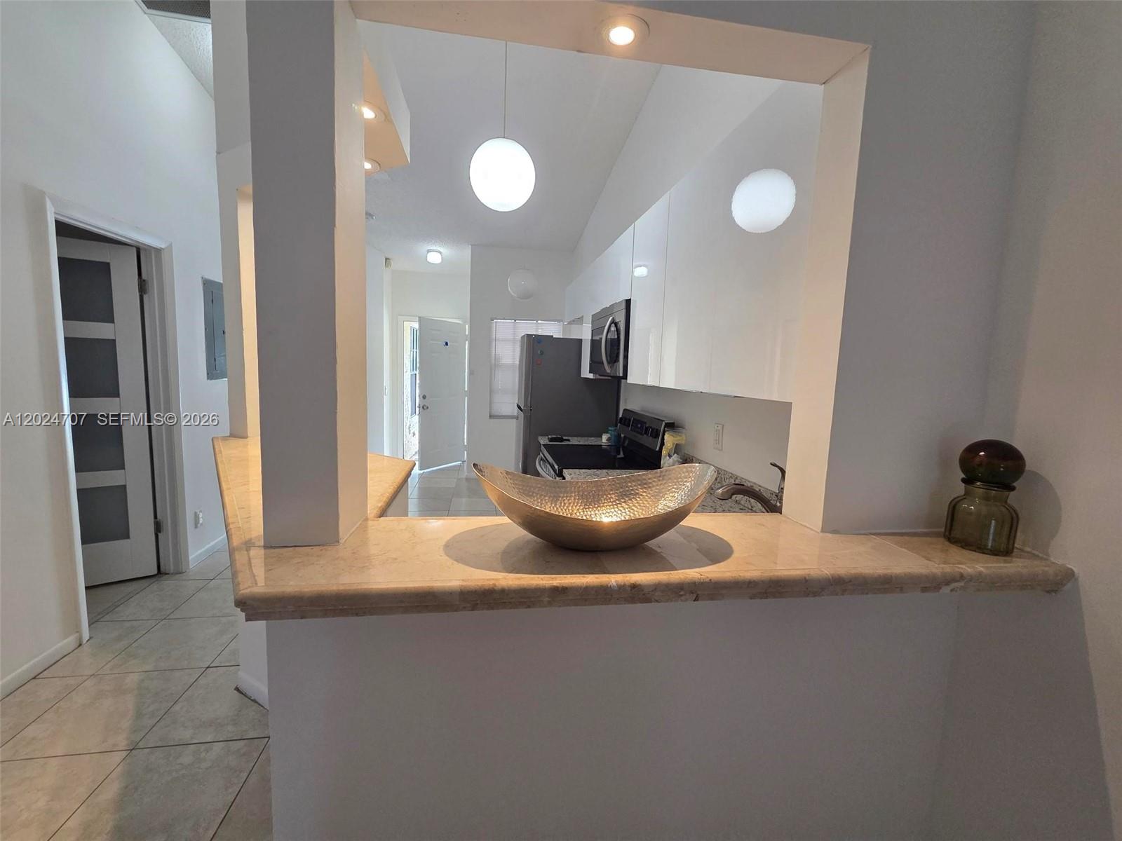 A kitchen with white cabinets and a stone countertop overlooks a living area — 3686 NW 83rd Ln # 3686, Sunrise FL 33351, SUNRISE, FL