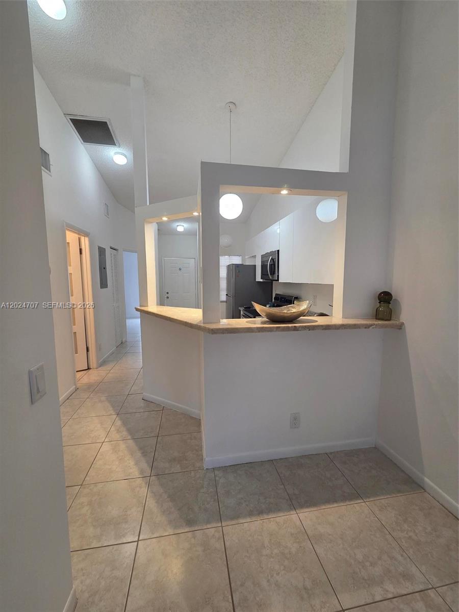A kitchen with white cabinets and a breakfast bar opens into a tiled hallway — 3686 NW 83rd Ln # 3686, Sunrise FL 33351, SUNRISE, FL