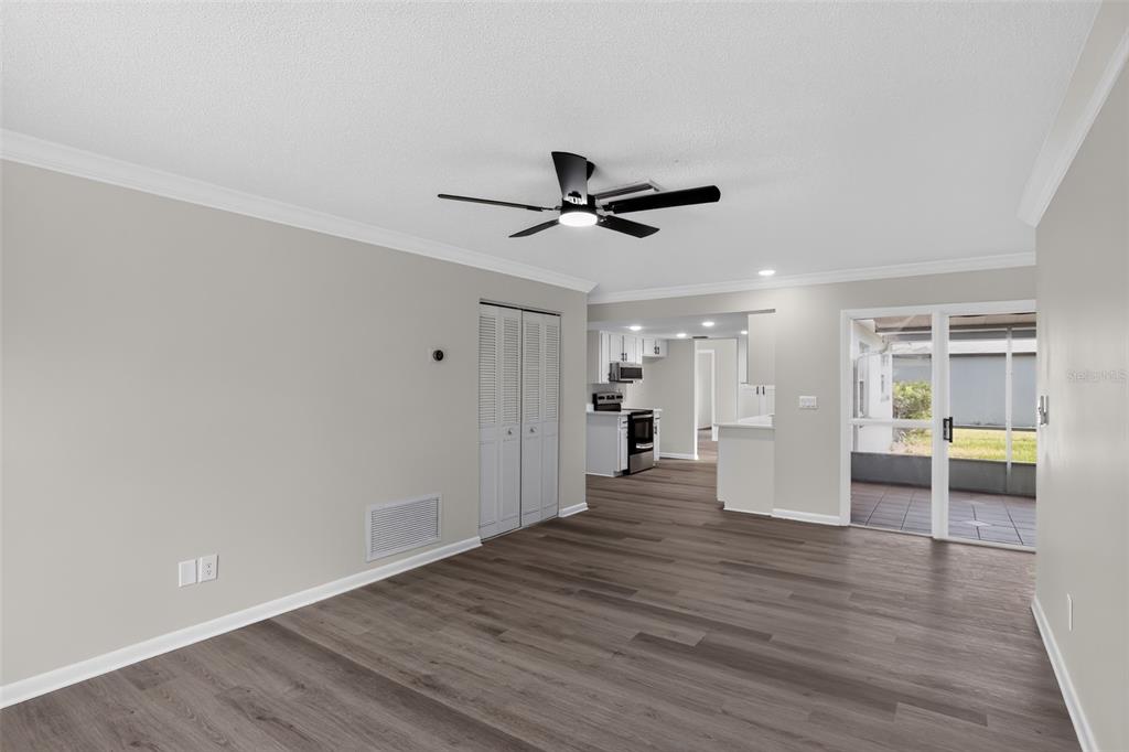 An open living area features wood-look flooring, a ceiling fan, and a sliding glass door — 1289 WORTHINGTON DRIVE, DELTONA, FL