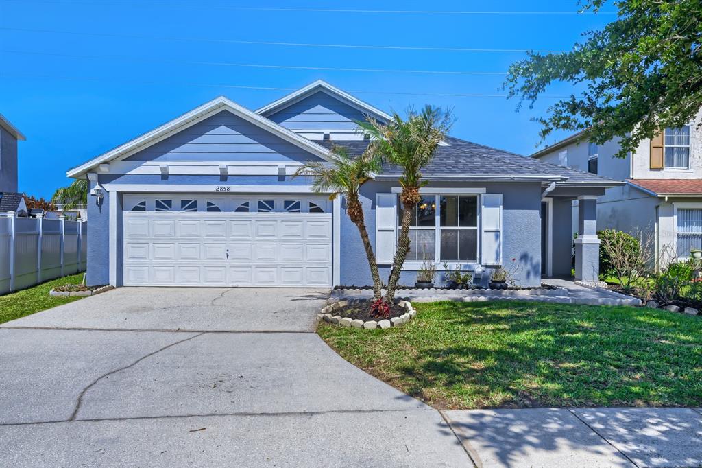 A blue single-story house features a two-car garage, a palm tree, and a concrete driveway — 2858 PAYNES PRAIRIE CIRCLE, KISSIMMEE, FL