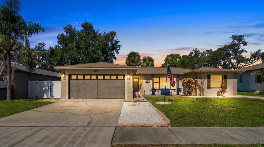 A single-story house with a tan exterior, a two-car garage, and a front yard — 1830 WILLOW OAK DRIVE W, PALM HARBOR, FL