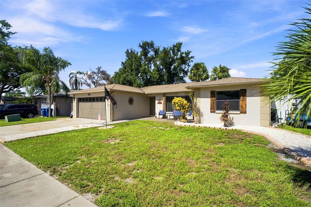 A single-story house with a tan exterior, a two-car garage, and a front lawn — 1830 WILLOW OAK DRIVE W, PALM HARBOR, FL