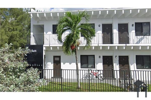 A two-story white apartment building features a palm tree and a black metal fence — FLORIDA CITY, FL