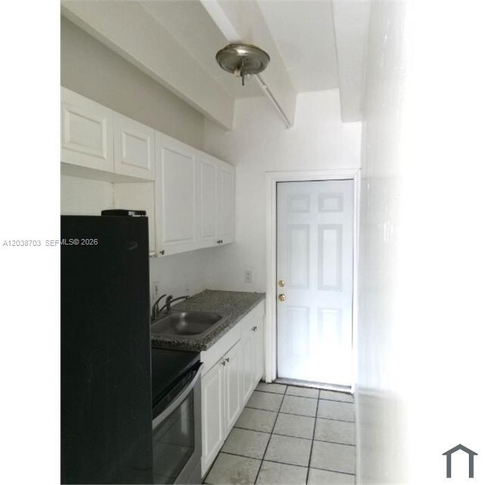 A kitchen features white cabinets, a granite countertop, a stainless steel sink, and a door — FLORIDA CITY, FL