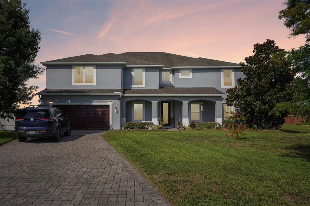 A two-story house with a gray stucco exterior, a paved driveway, and a dark garage door — 17407 BELLA NOVA DRIVE, ORLANDO, FL