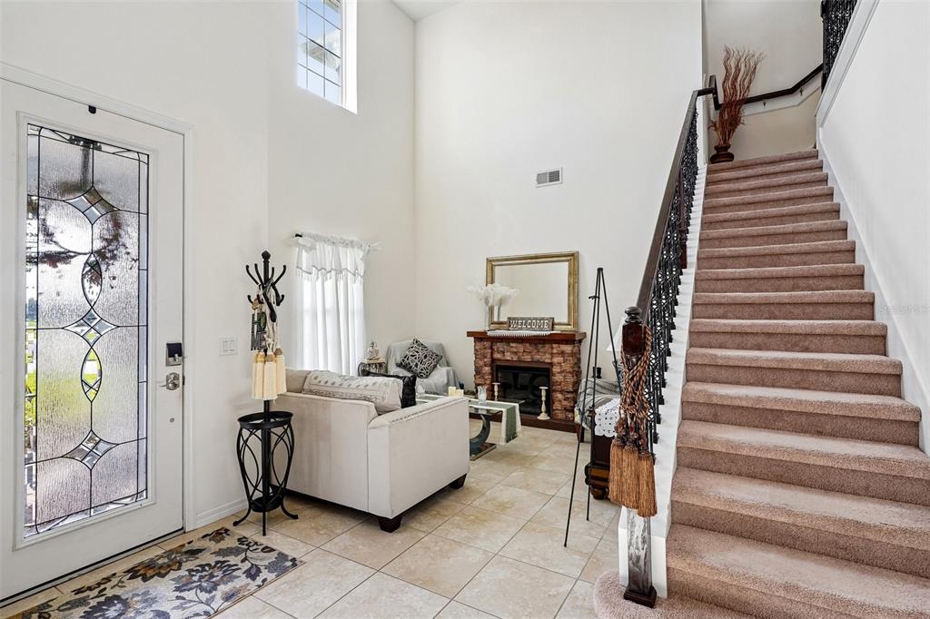 An entryway features a carpeted staircase, tile flooring, a fireplace, and a front door — 17407 BELLA NOVA DRIVE, ORLANDO, FL