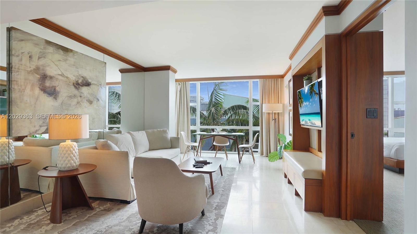 A living room features a white sofa, a dining area, and a wall-mounted television — 6801 Collins Ave # 315, Miami Beach FL 33141, MIAMI BEACH, FL