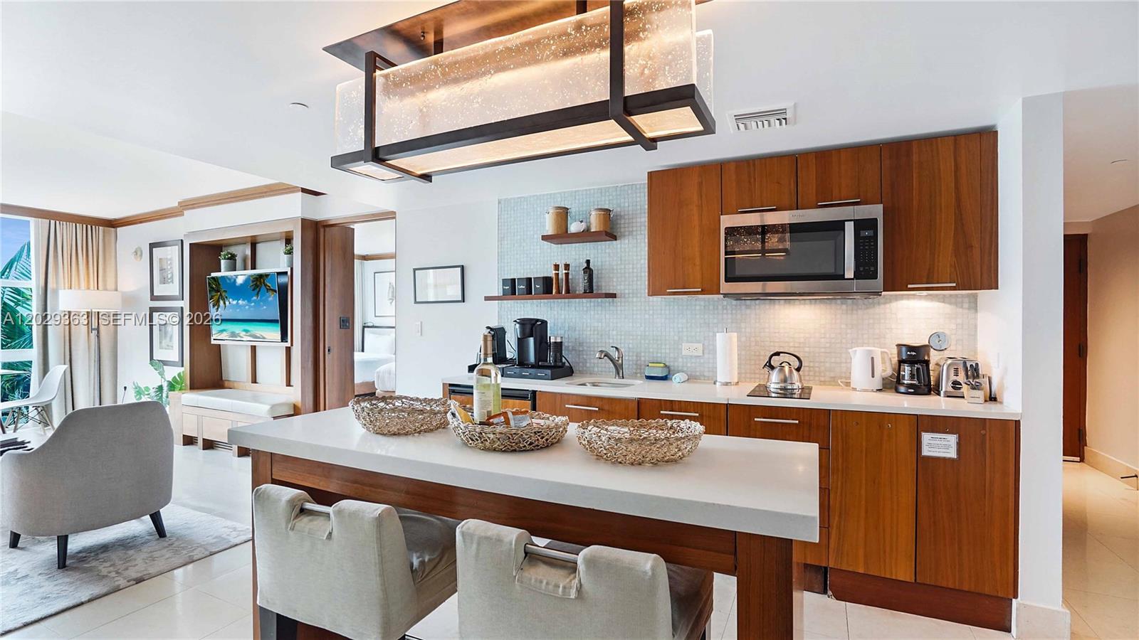 A modern kitchen features wood cabinets, a white countertop island, and a rectangular pendant light — 6801 Collins Ave # 315, Miami Beach FL 33141, MIAMI BEACH, FL