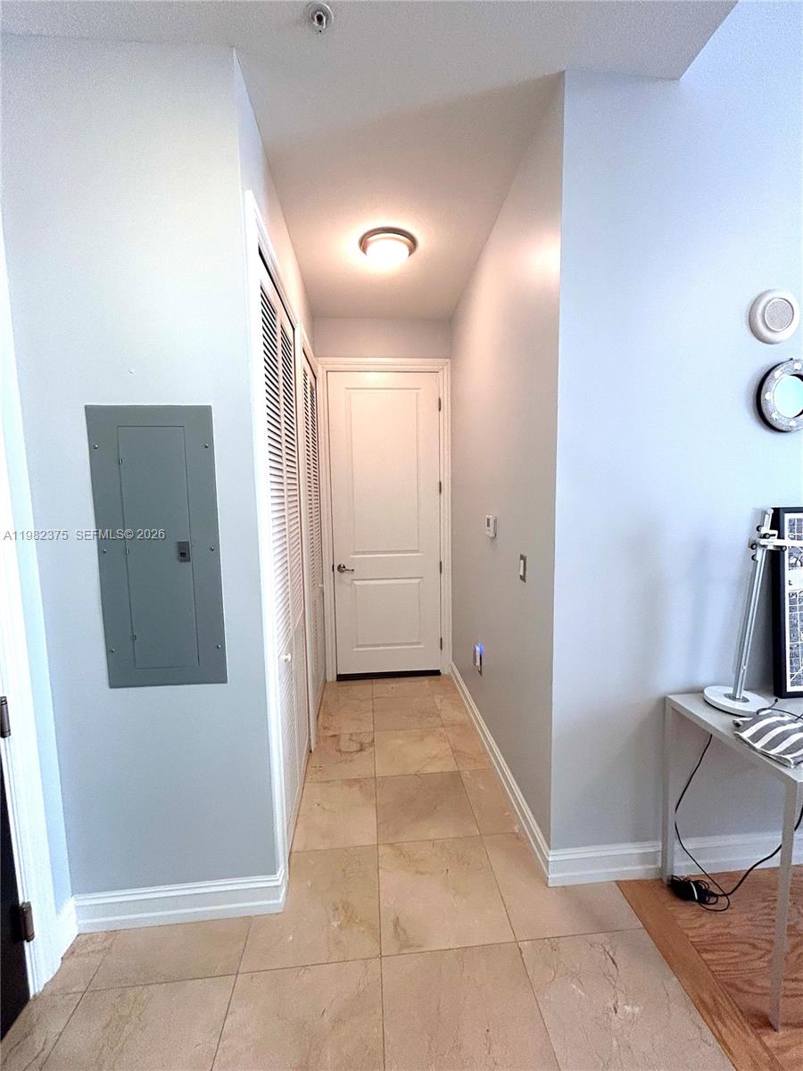 A hallway features light-colored tile flooring, a white door, and a gray electrical panel — 1805 Ponce De Leon Blvd # 626, Coral Gables FL 33134, CORAL GABLES, FL