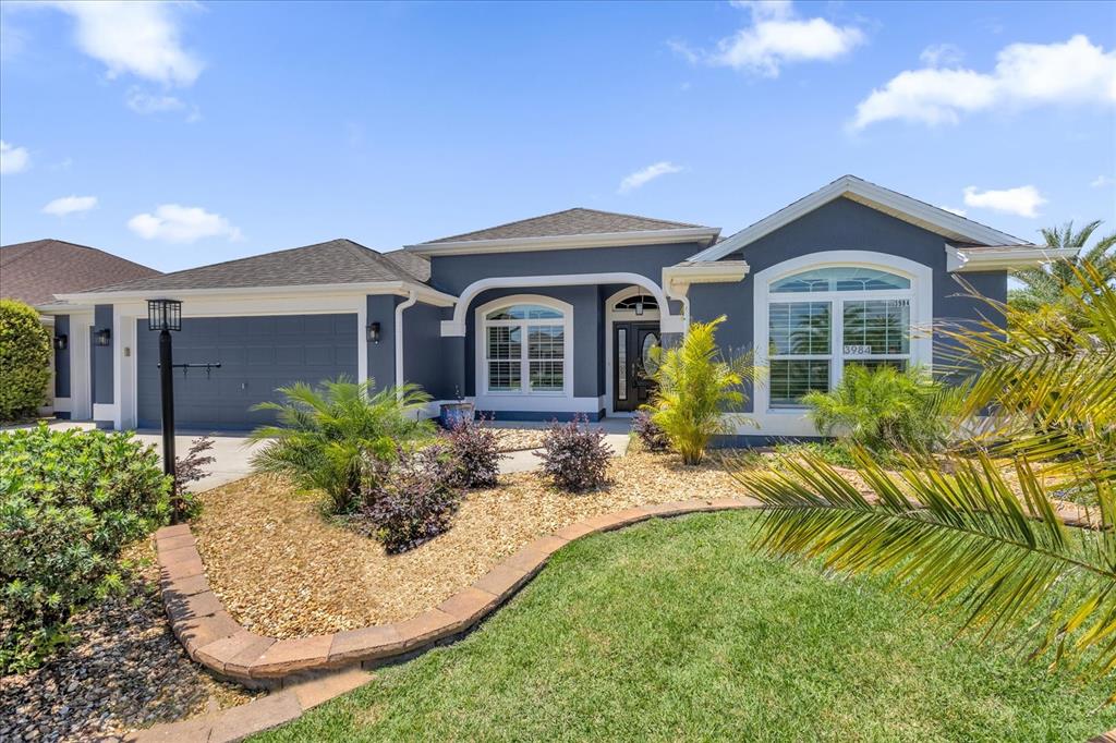 A single-story house with dark gray siding, a garage, and a landscaped front yard — 3984 MCDOWELL DRIVE, THE VILLAGES, FL