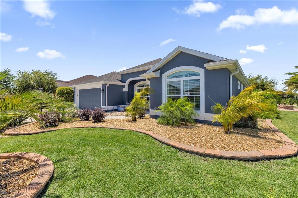 A dark blue single-story house with a garage, arched window, and landscaped front yard — 3984 MCDOWELL DRIVE, THE VILLAGES, FL