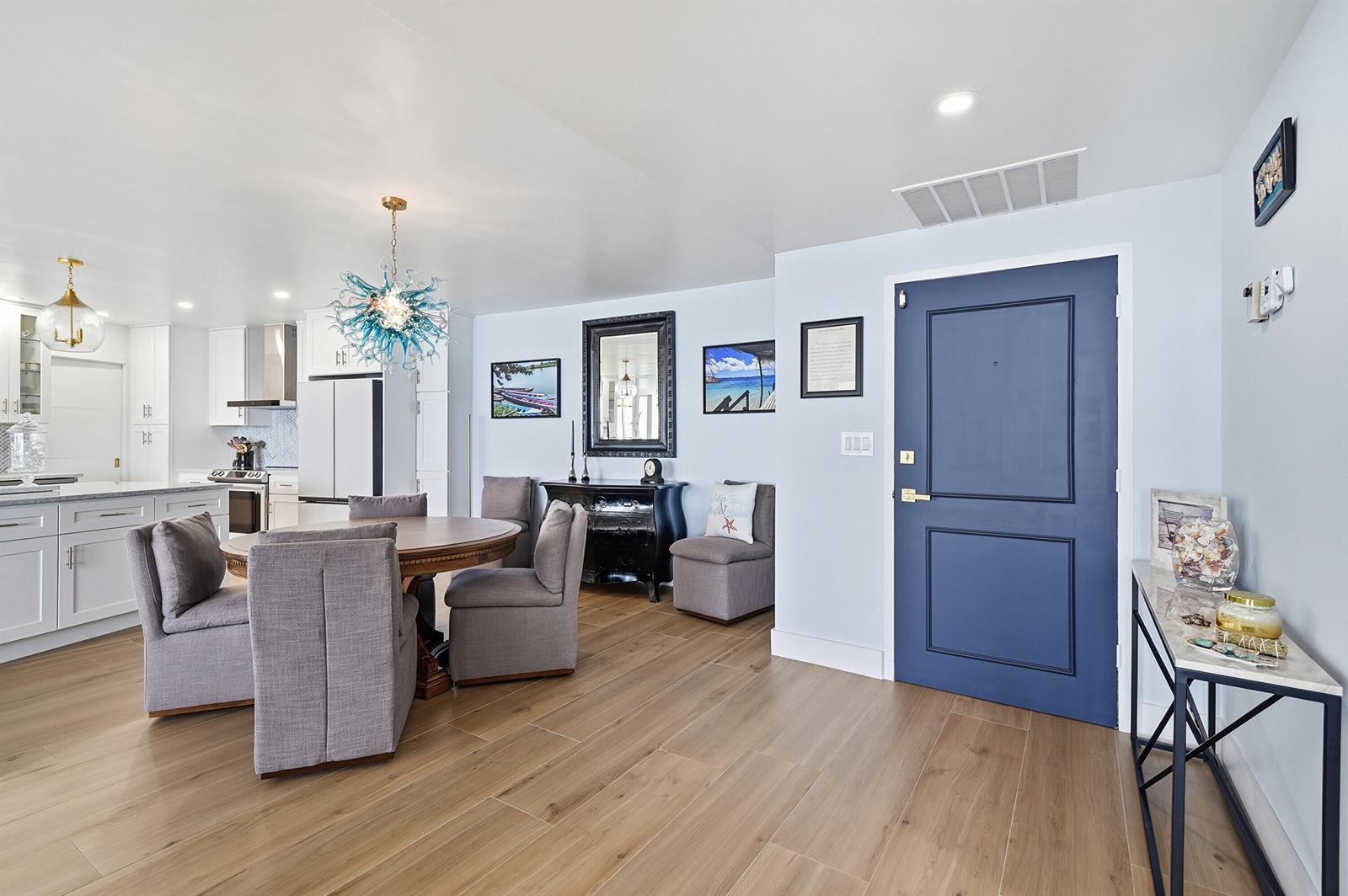 A dining area and entryway feature light wood floors, a blue door, and gray furniture — 700 S Ocean Boulevard # 803, Boca Raton FL 33432, BOCA RATON, FL