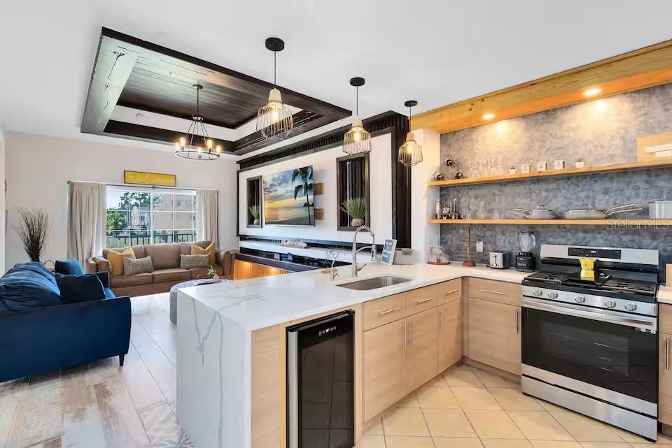 A modern kitchen with light wood cabinets and a white marble island overlooks a living area — 1326 SEVEN EAGLES COURT UNIT 1326, KISSIMMEE, FL
