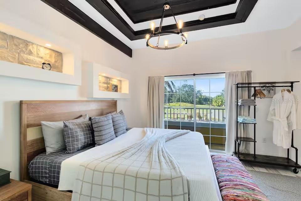 A bedroom features a wooden bed, recessed wall niches, a tray ceiling, and balcony views — 1326 SEVEN EAGLES COURT UNIT 1326, KISSIMMEE, FL