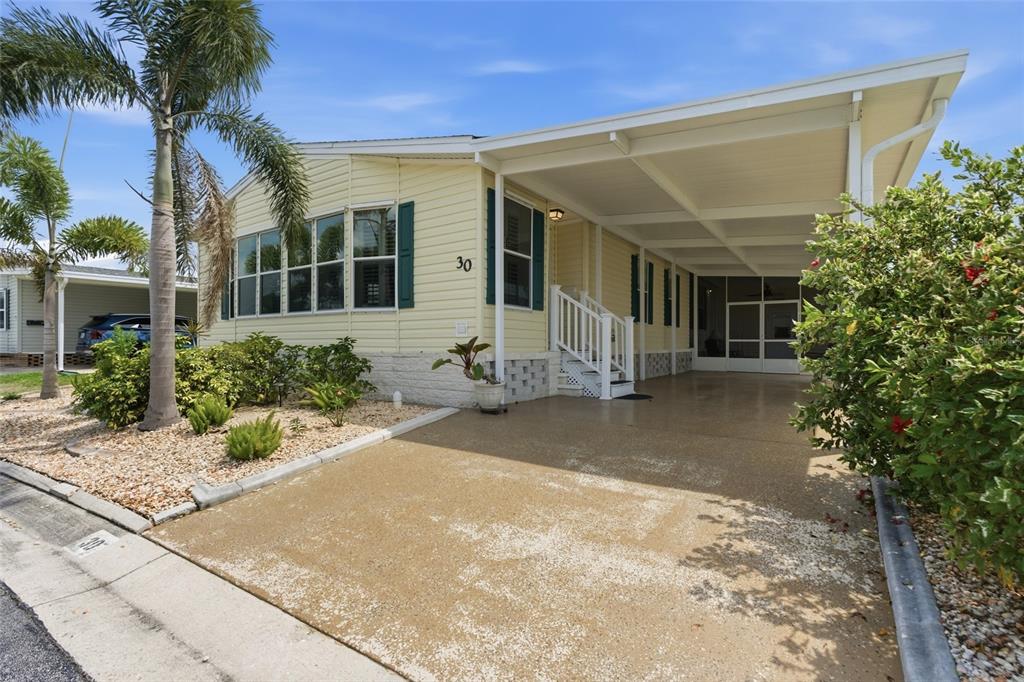 A light yellow manufactured home with a carport, front steps, and palm trees — 15550 BURNT STORE ROAD UNIT 30, PUNTA GORDA, FL
