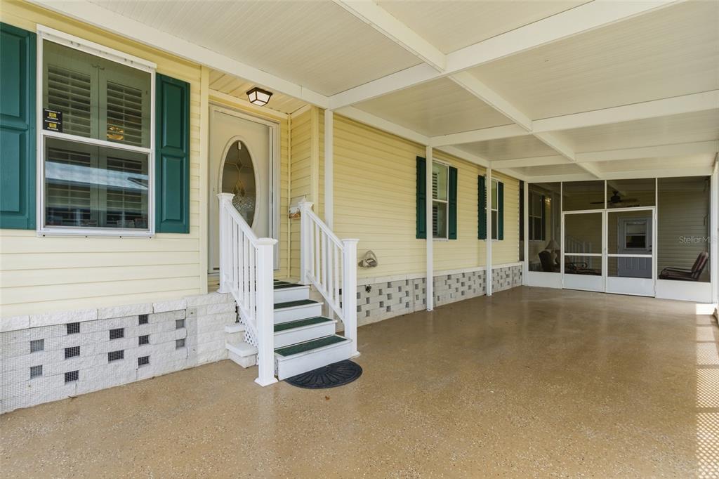 A yellow mobile home exterior features a covered carport, white stairs, and a screened porch — 15550 BURNT STORE ROAD UNIT 30, PUNTA GORDA, FL
