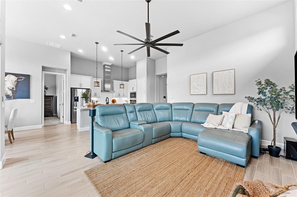 A living room features a blue sectional sofa, a jute rug, and an open kitchen — 257 MOSAIC BOULEVARD, DAYTONA BEACH, FL