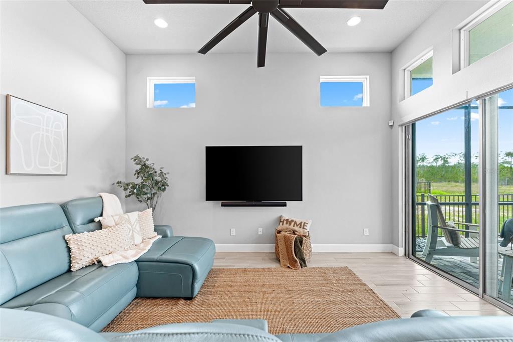 A living room features a blue sectional sofa, a wall-mounted television, and sliding glass doors — 257 MOSAIC BOULEVARD, DAYTONA BEACH, FL