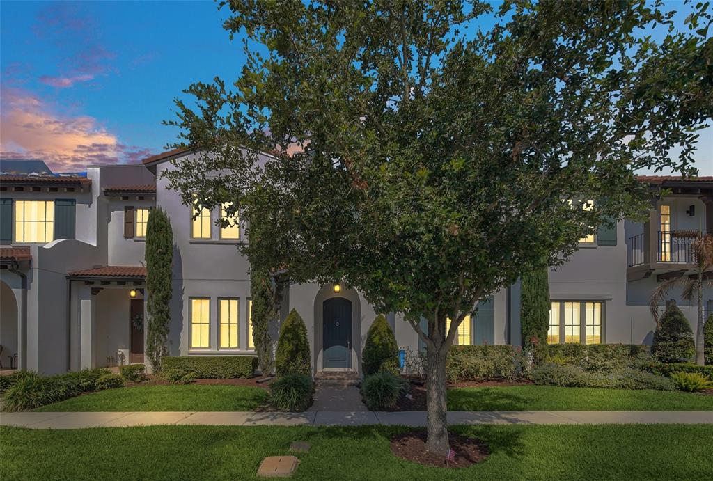 A two-story townhouse with a light-colored stucco exterior, a tiled roof, and a front tree — 8878 BISMARCK PALM DRIVE, WINTER GARDEN, FL