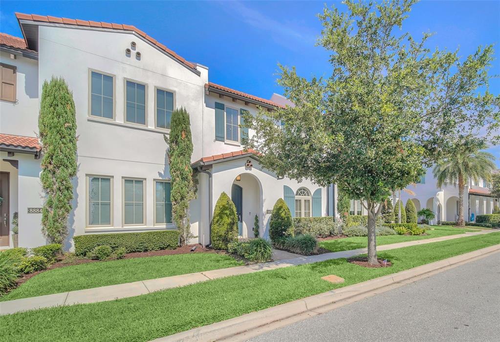 A two-story white stucco townhouse with a tile roof and a landscaped front yard — 8878 BISMARCK PALM DRIVE, WINTER GARDEN, FL