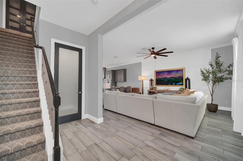 A staircase with patterned carpet leads to a living room with gray tile flooring — 8878 BISMARCK PALM DRIVE, WINTER GARDEN, FL