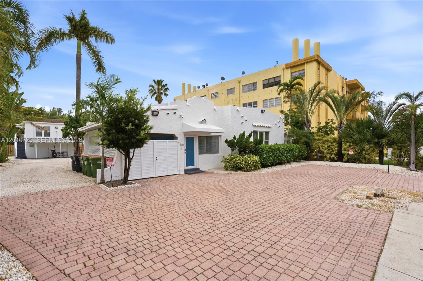 A white stucco building with a blue door sits behind a brick-paved driveway — 340 NE 125th St, North Miami FL 33161, NORTH MIAMI, FL