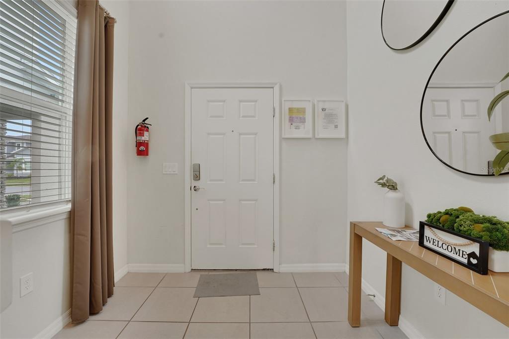 An entryway features a white front door, tiled flooring, a console table, and a fire extinguisher — 4450 KAIPO ROAD, DAVENPORT, FL