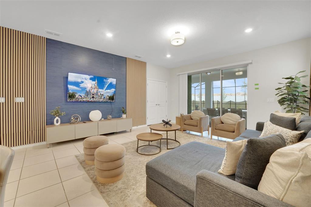 A living room features a blue accent wall with wood slats, a television, and furniture — 4450 KAIPO ROAD, DAVENPORT, FL