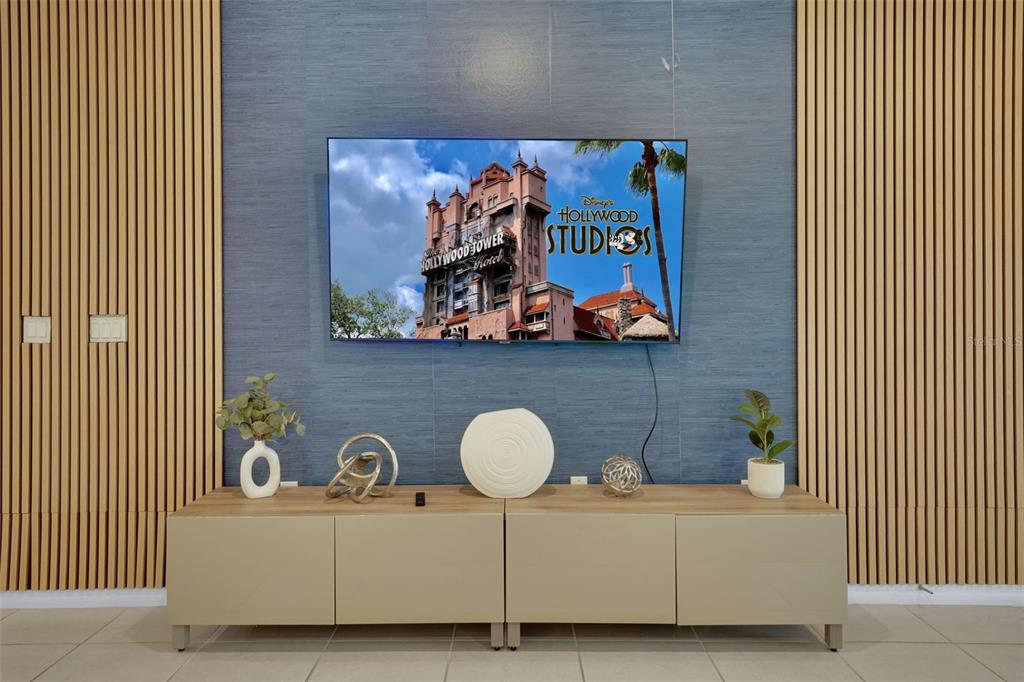 A wall-mounted television displays a Disney theme park image above a modern media console — 4450 KAIPO ROAD, DAVENPORT, FL