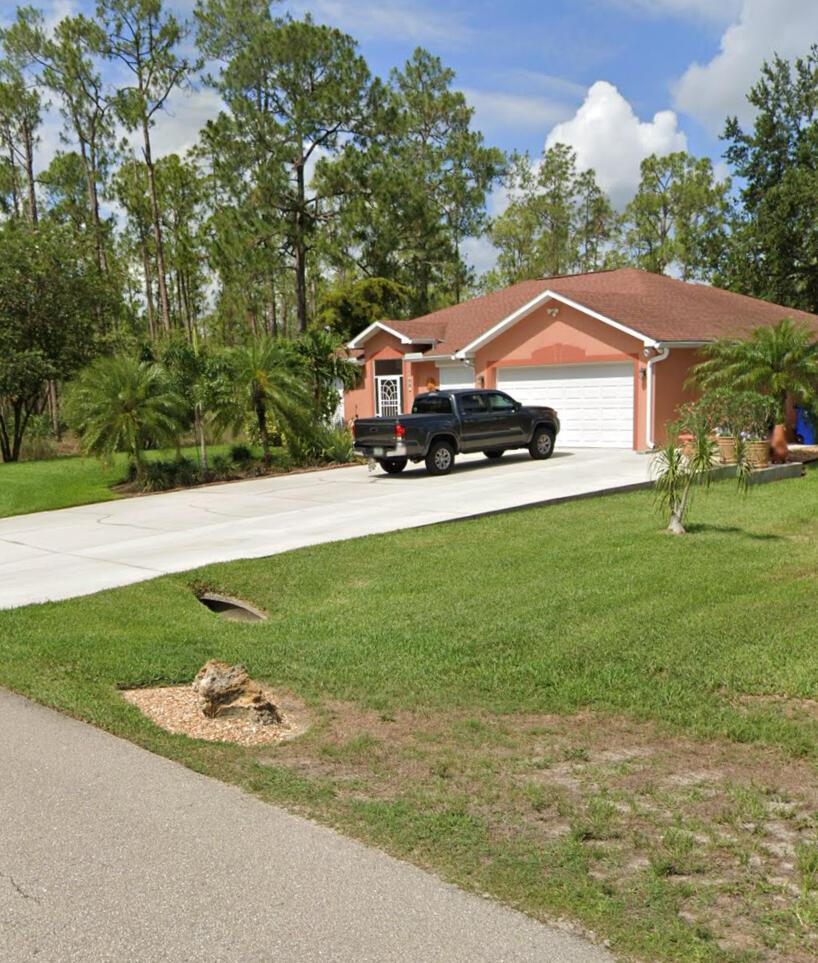 A single-story peach-colored house with a two-car garage and a pickup truck in the driveway — 109 Moore Avenue, Lehigh Acres FL 33936, LEHIGH ACRES, FL