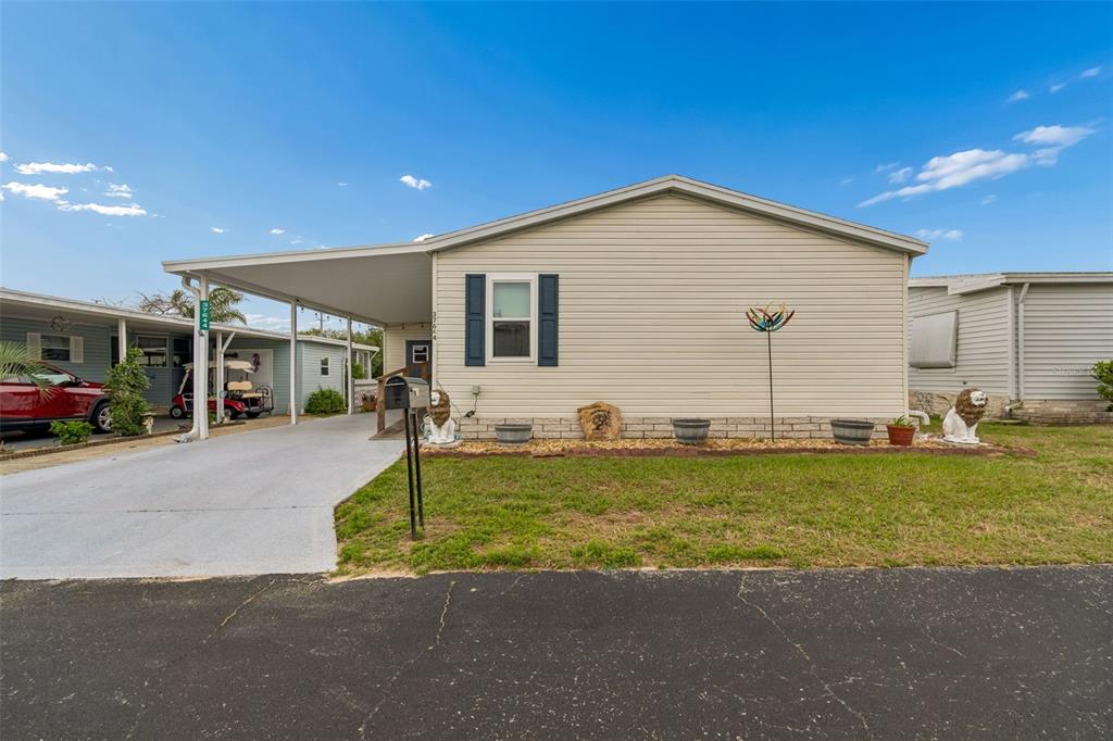 A single-story mobile home with a carport, tan siding, and a small front lawn — 37644 PINATA AVENUE, ZEPHYRHILLS, FL