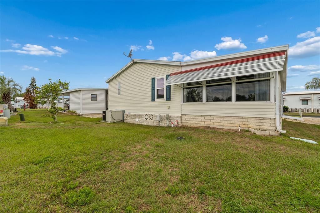 A side view of a light-colored mobile home with a brick base and attached sunroom — 37644 PINATA AVENUE, ZEPHYRHILLS, FL