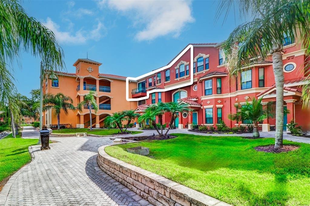 A multi-story apartment building with a highlighted balcony and red stucco exterior — 2722 VIA TIVOLI UNIT 435B, CLEARWATER, FL