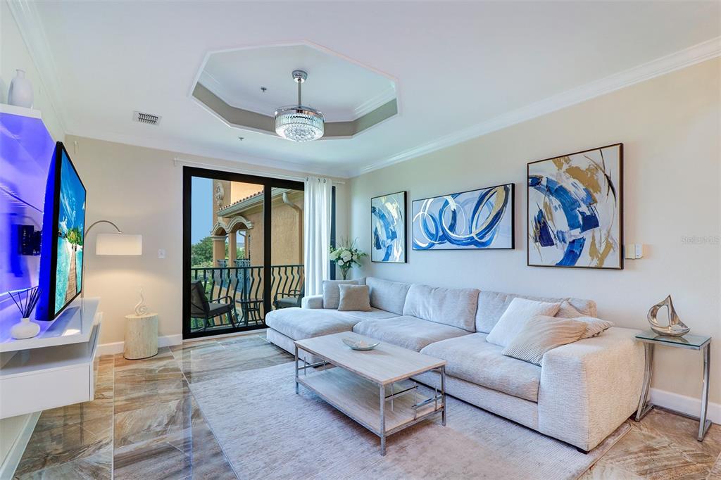 A living room features a sectional sofa, a coffee table, and a balcony with seating — 2722 VIA TIVOLI UNIT 435B, CLEARWATER, FL