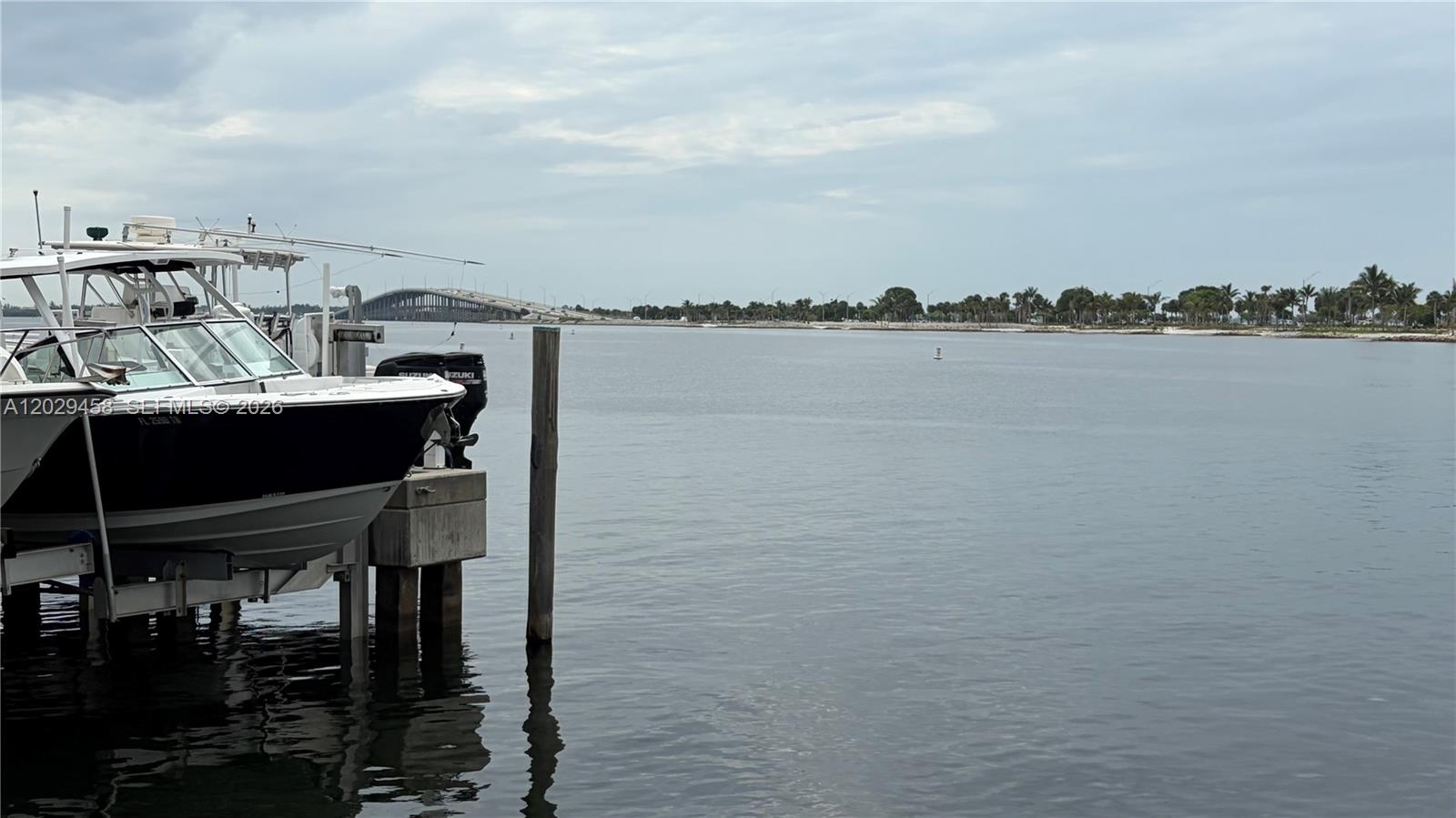 A boat is docked at a pier overlooking a bay with a bridge in the distance — 150 SE 25th Rd, Miami FL 33131, MIAMI, FL