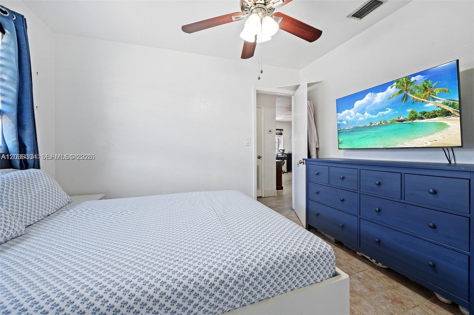 A bedroom features a bed, a blue dresser with a wall-mounted television, and a ceiling fan — 5120 SW 26th Ave # 2, Dania Beach FL 33312, DANIA BEACH, FL