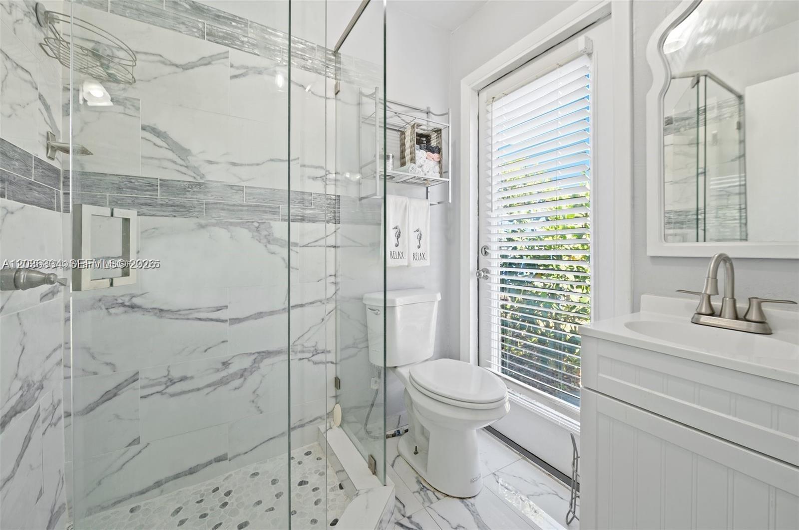 A bathroom features a marble-tiled walk-in shower, a white toilet, and a vanity with sink — 5120 SW 26th Ave # 2, Dania Beach FL 33312, DANIA BEACH, FL