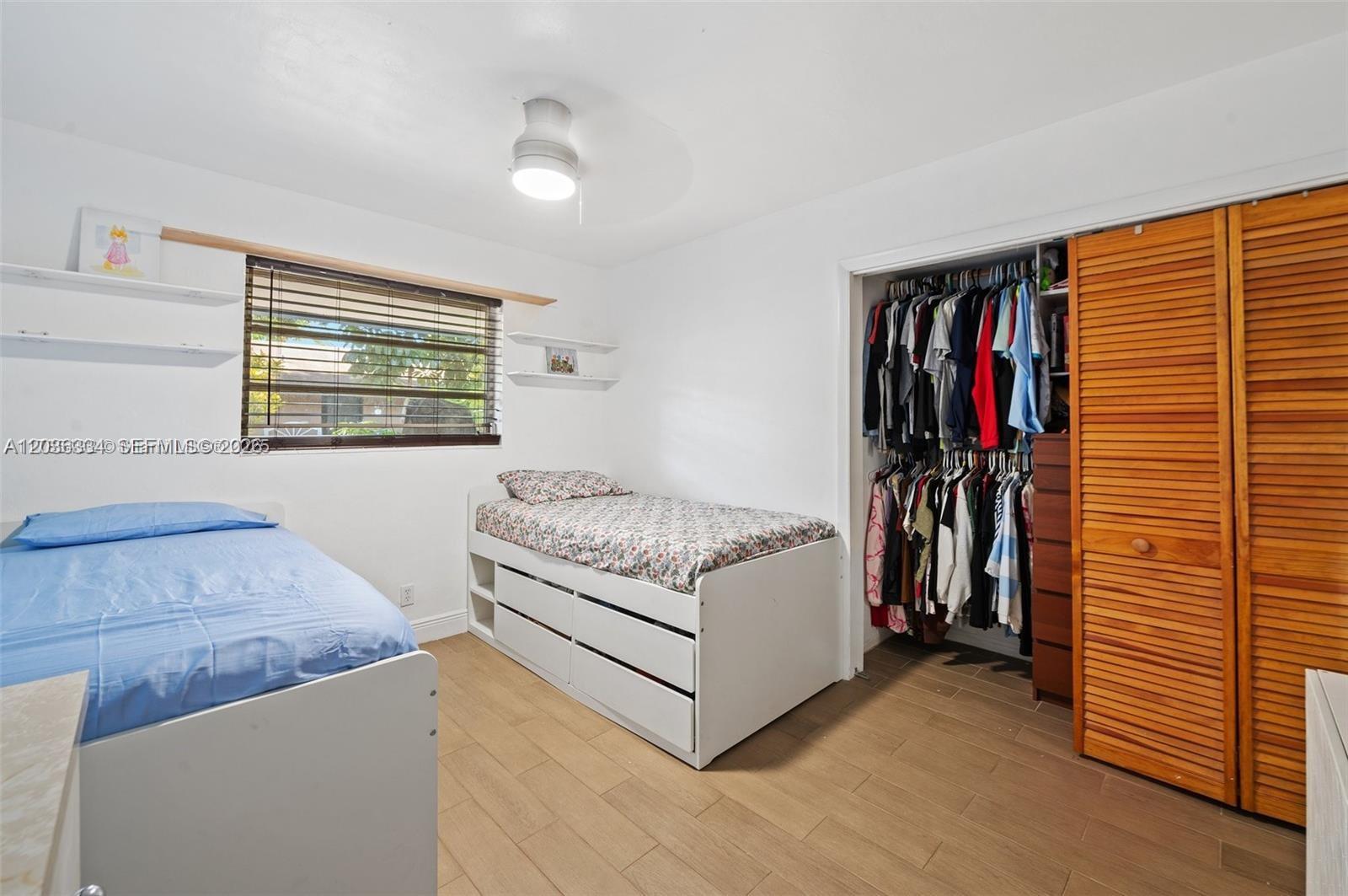 A bedroom features two beds, a closet with wooden louvered doors, and light wood flooring — 5120 SW 26th Ave # 2, Dania Beach FL 33312, DANIA BEACH, FL
