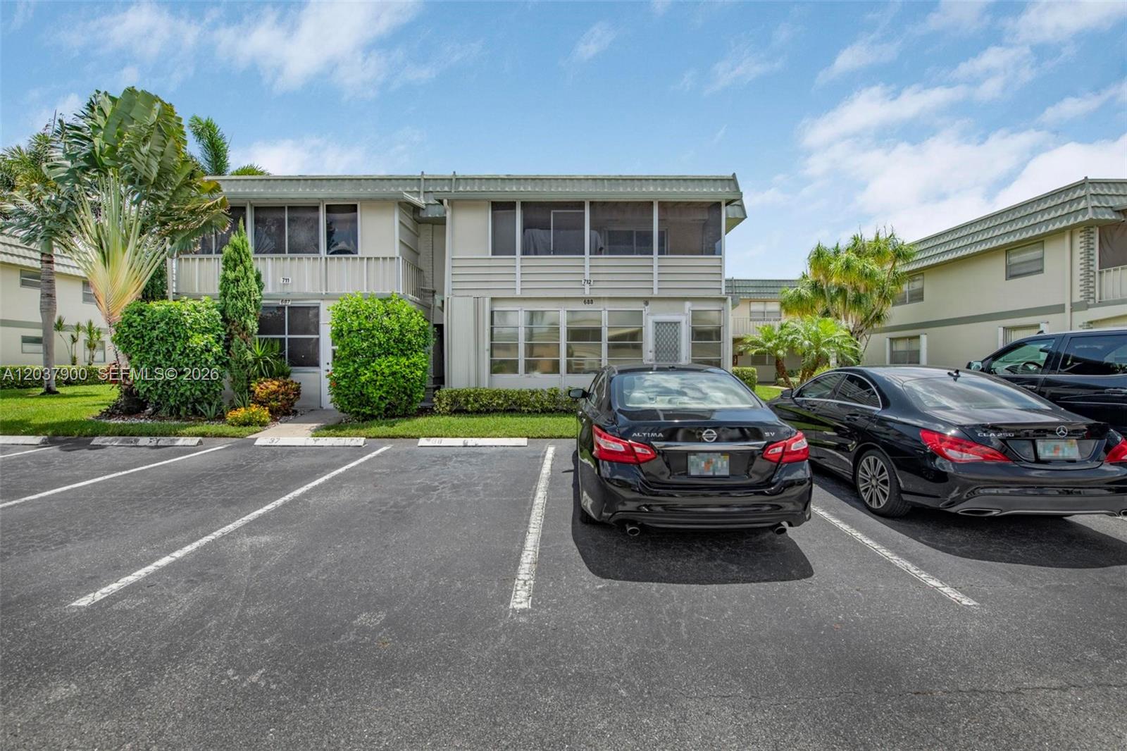 A two-story apartment building exterior features screened balconies and a parking lot in front — 712 Monaco O # 712, Delray Beach FL 33446, DELRAY BEACH, FL