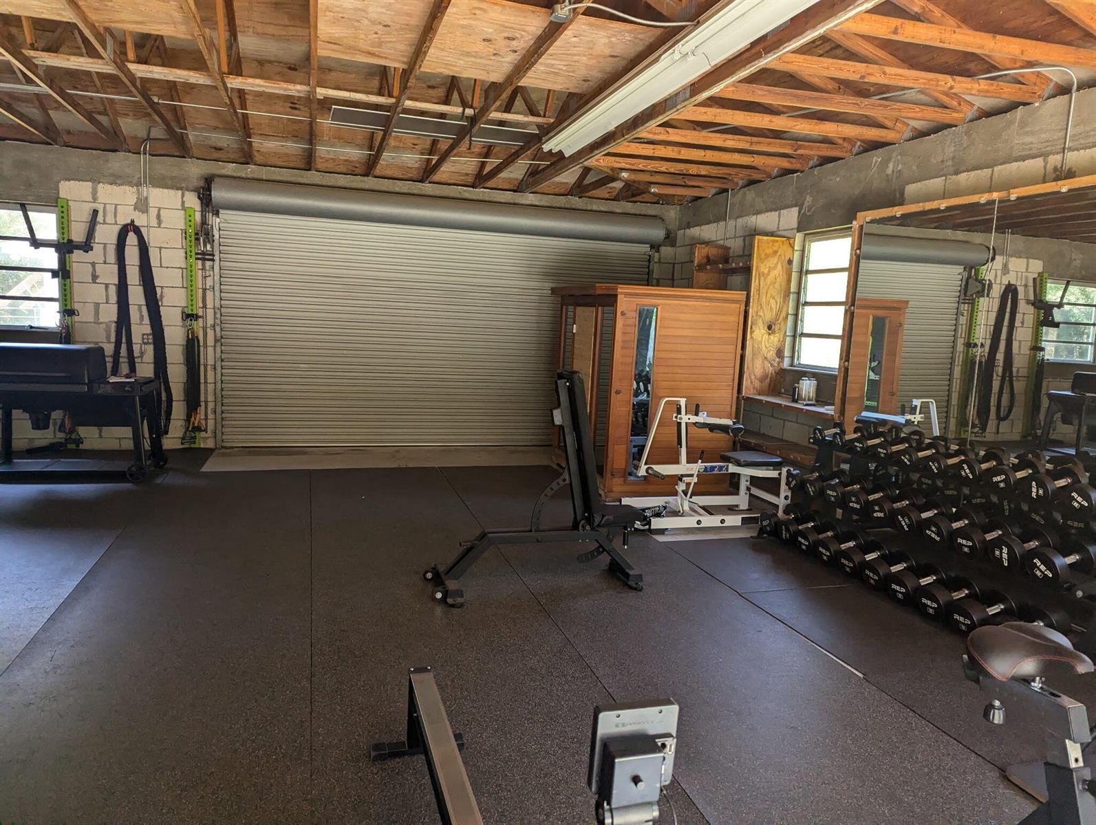 A garage gym features rubber flooring, a weight rack, dumbbells, a sauna, and exposed rafters — 16824 N 130th Ave Avenue N, FL 33478, FL