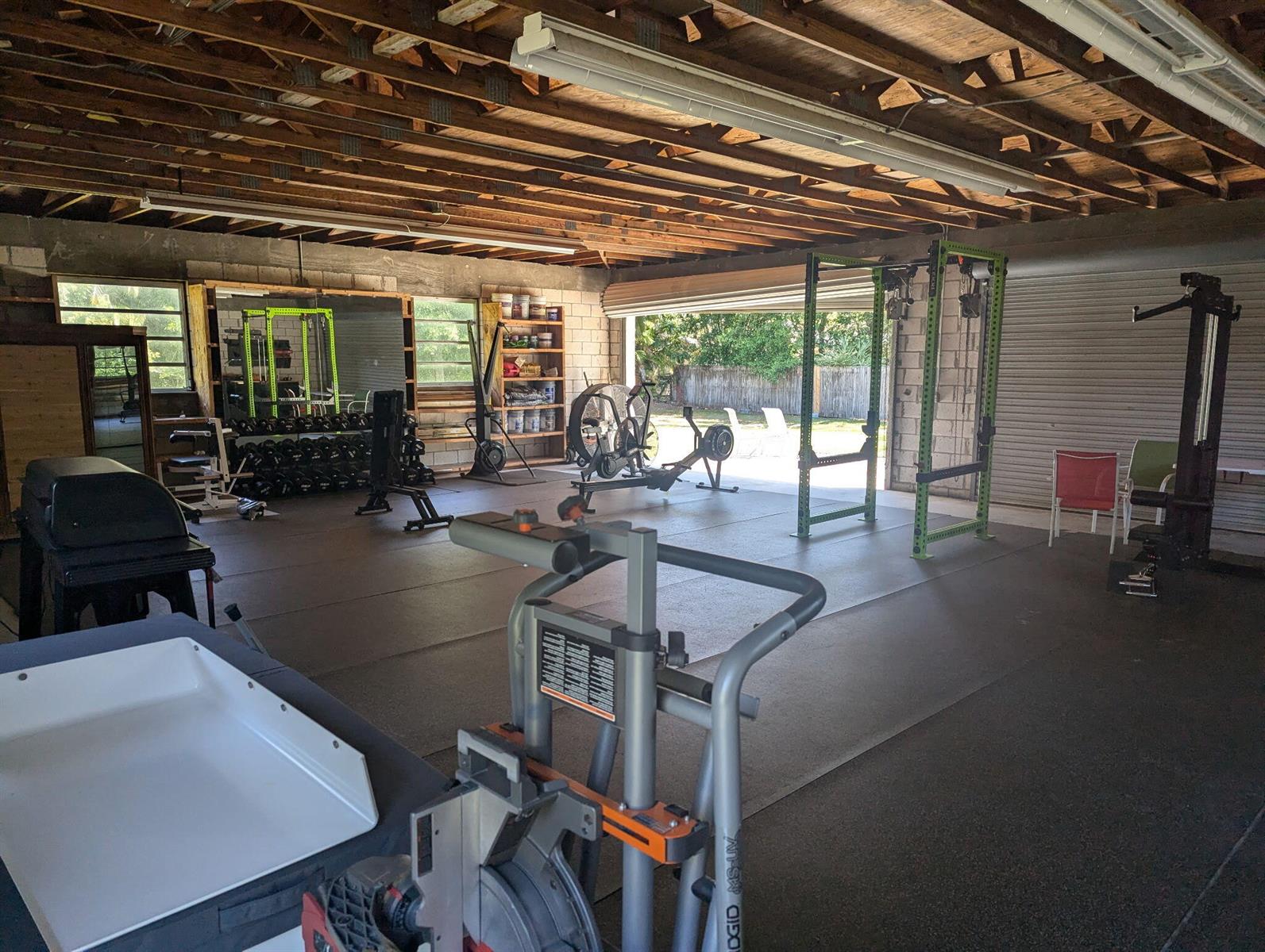 A spacious garage converted into a home gym with rubber flooring and various exercise equipment — 16824 N 130th Ave Avenue N, FL 33478, FL